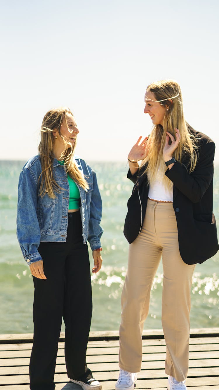 Friends Chatting While Standing On Wooden Dock