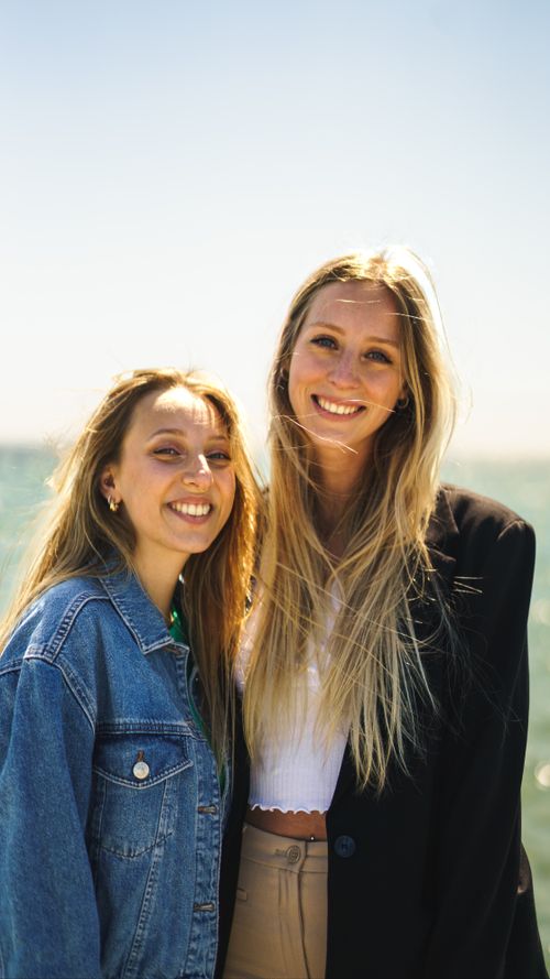 Free Two happy women with blond hair smiling together by the seaside on a sunny day. Stock Photo