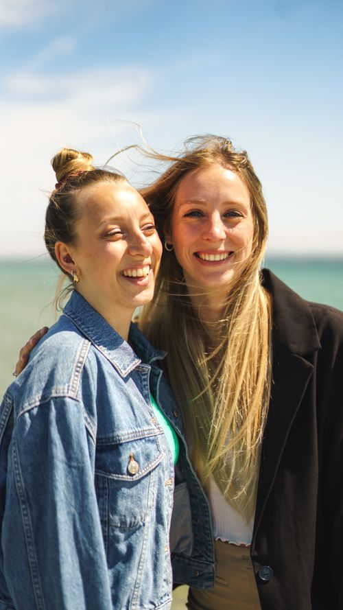 Free Two young women enjoying a sunny day at the beach, smiling and carefree. Stock Photo