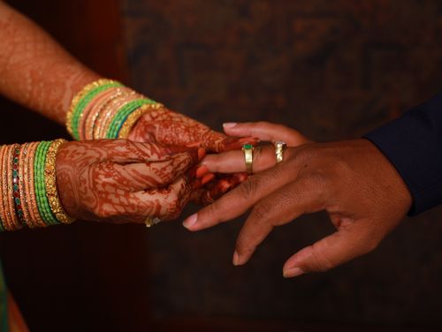 Free Close-up of a bride and groom exchanging rings with ornate henna and jewelry. Stock Photo