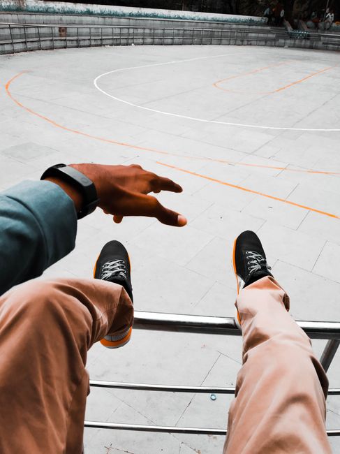 A view of a person relaxing by an empty basketball court with sneakers visible.