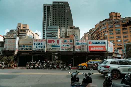 Busy urban street with scooters and high-rise buildings under a clear sky.