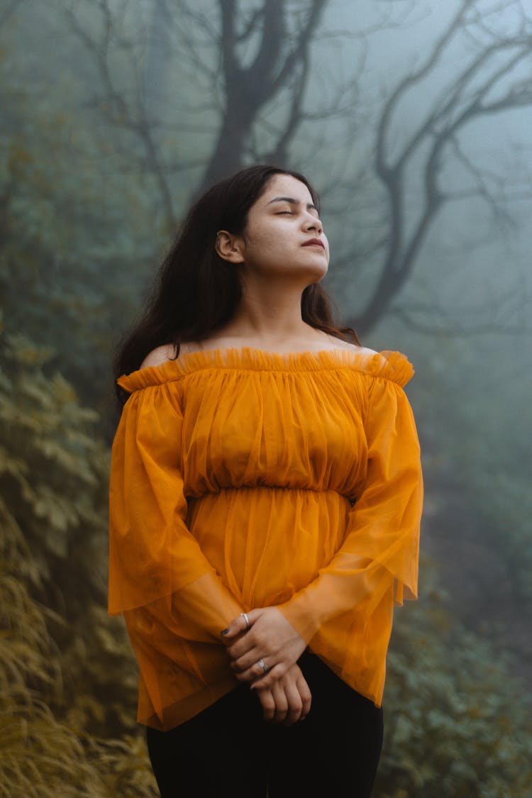 A Woman In Yellow Off Shoulder Top With Her Eyes Closed