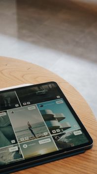 Close-up of a modern tablet displaying a photo gallery, placed on a wooden table in an Istanbul cafe.