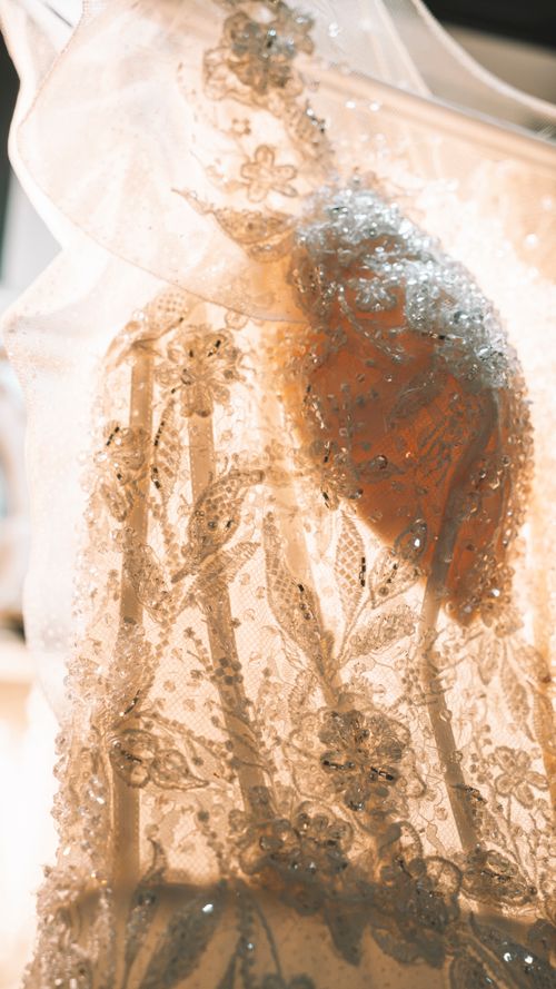 Free Close-up shot of a wedding dress showcasing elegant lace and beadwork under warm lighting. Stock Photo