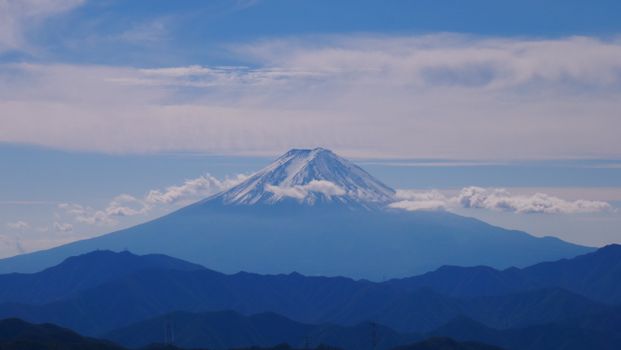 A breathtaking view of Mount Fuji surrounded by clouds under a clear blue sky.