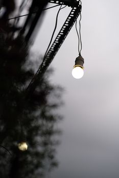 Moody outdoor scene with a hanging light bulb amidst fog at dusk, creating a serene ambiance.