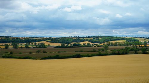 Free Beautiful aerial view of the scenic farmland in Harlington, England, featuring lush green hills and a cloudy blue sky. Stock Photo