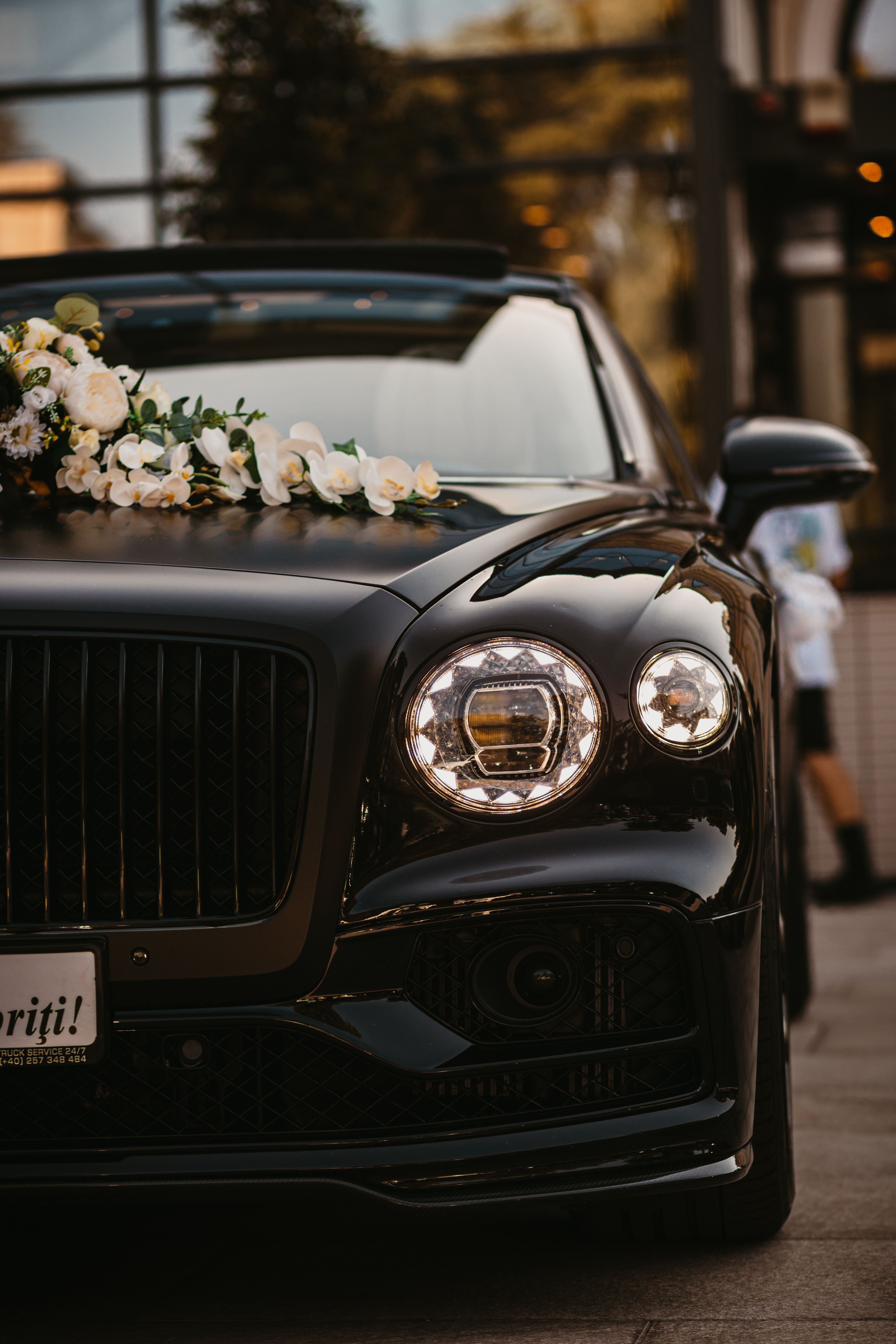 Voiture noire de luxe décorée de fleurs pour un mariage, garée à l'extérieur