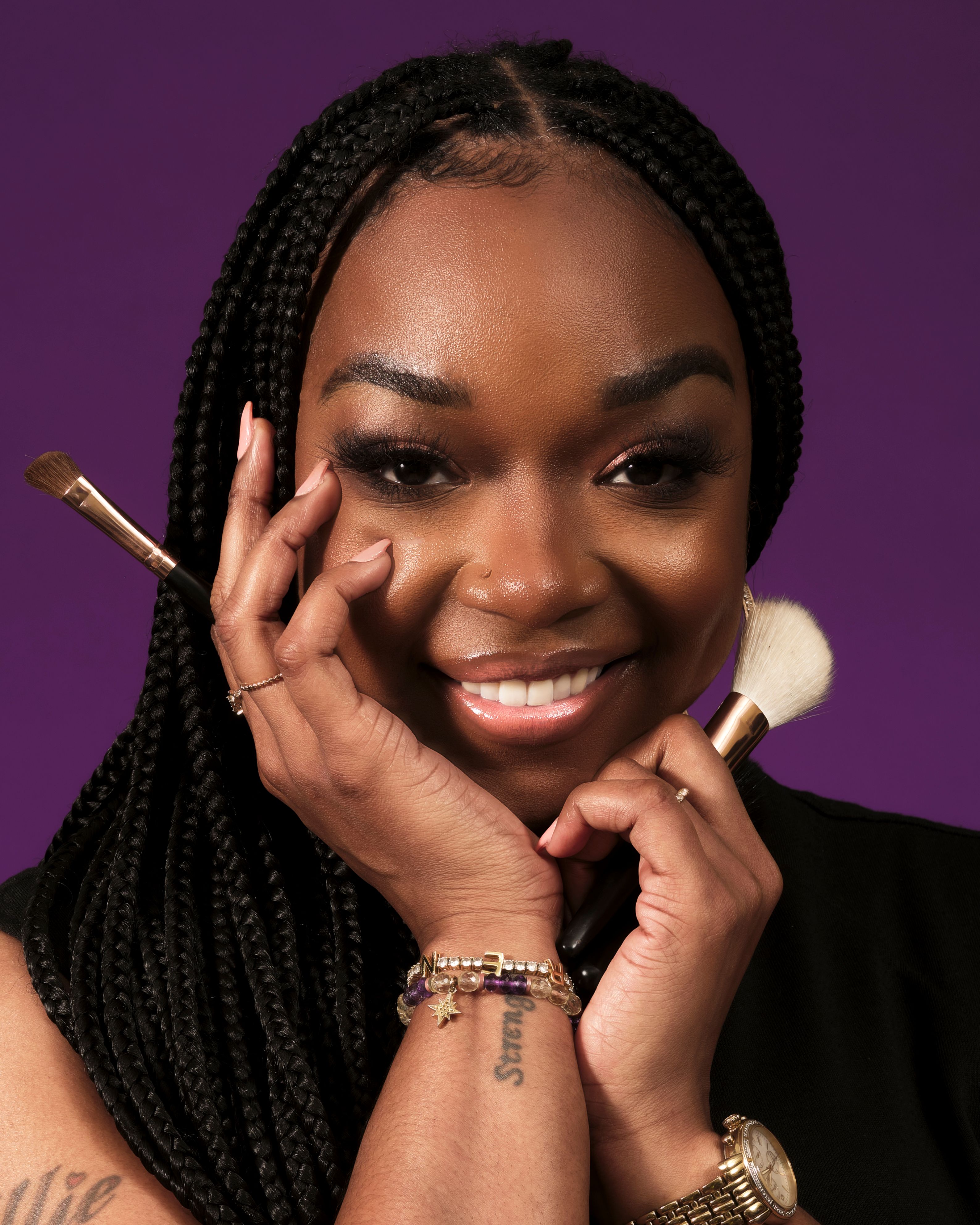 Glamorous portrait of a smiling woman posing with makeup brushes, showcasing beauty and confidence.