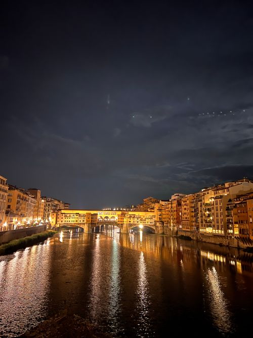 Free Night view of Ponte Vecchio reflecting in the Arno River, Florence's historic bridge illuminated. Stock Photo