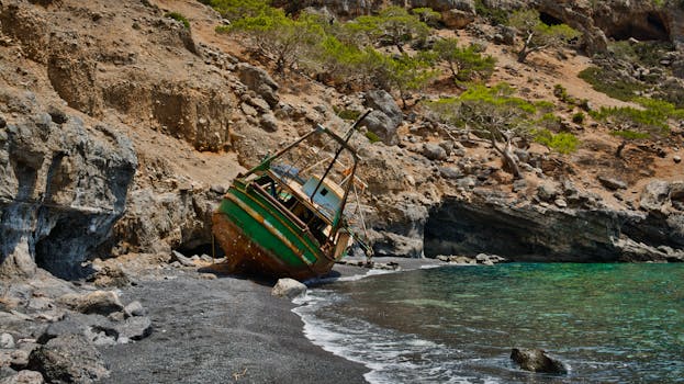 Rustic sunken ship on black sand beach in Rethymno, Greece at daytime.