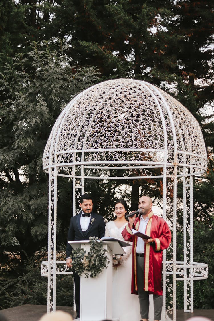 Couple Getting Married Under White Gazebo