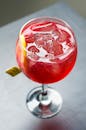 玻璃杯中的冰镇红色鸡尾酒，配有冰块和柑橘装饰