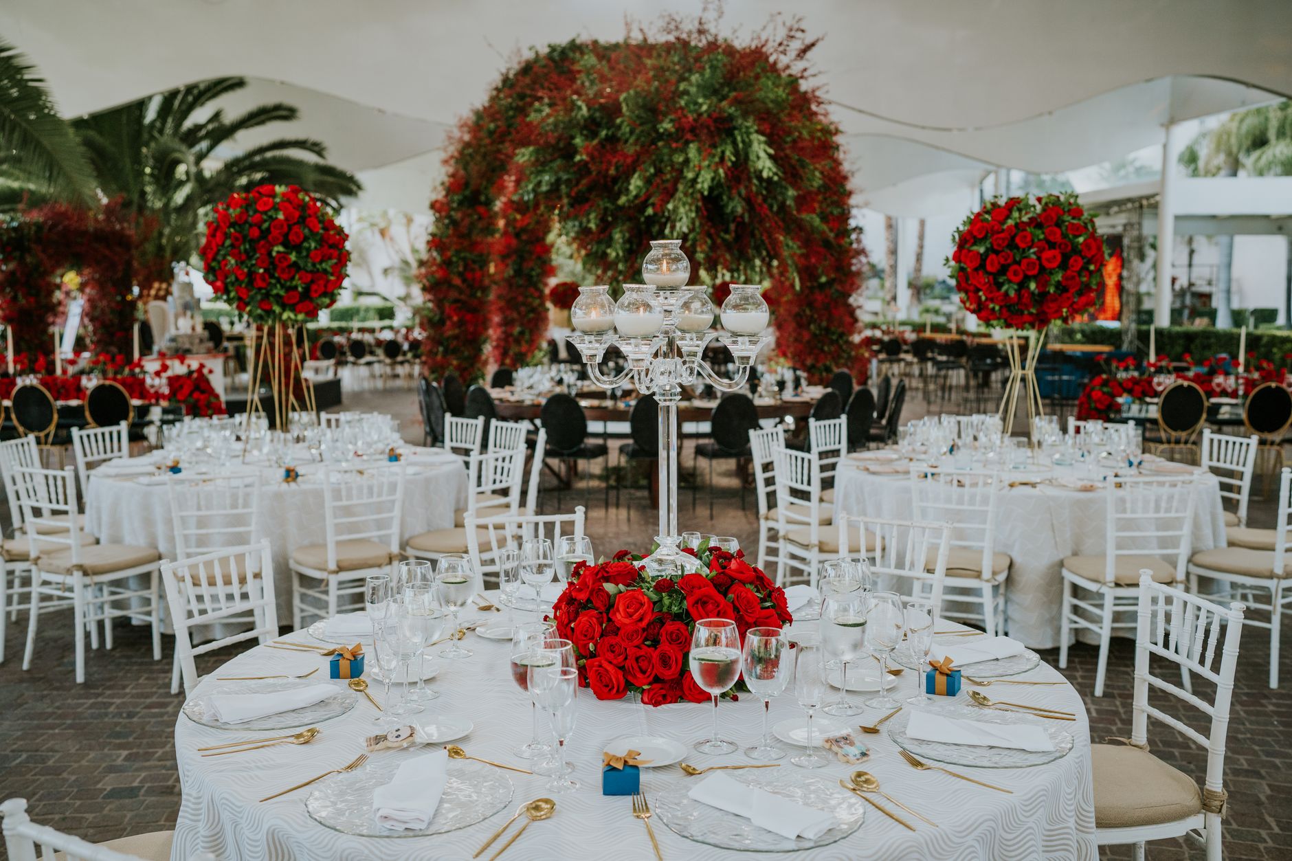 Art deco wedding table setting with gold geometric chargers, tall crystal candlesticks, and white calla lily centerpieces