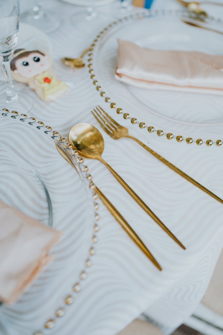 A Golden Spoon And Fork Between Glass Plates