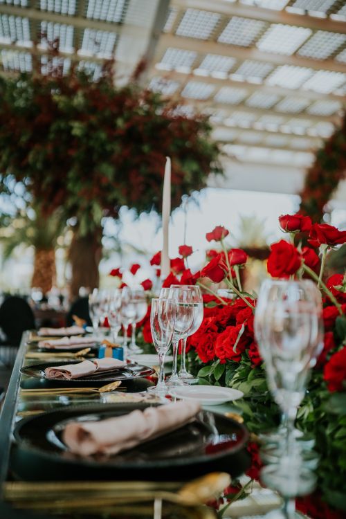 Free A luxurious outdoor table setting featuring red roses, cutlery, and candles under natural light. Stock Photo