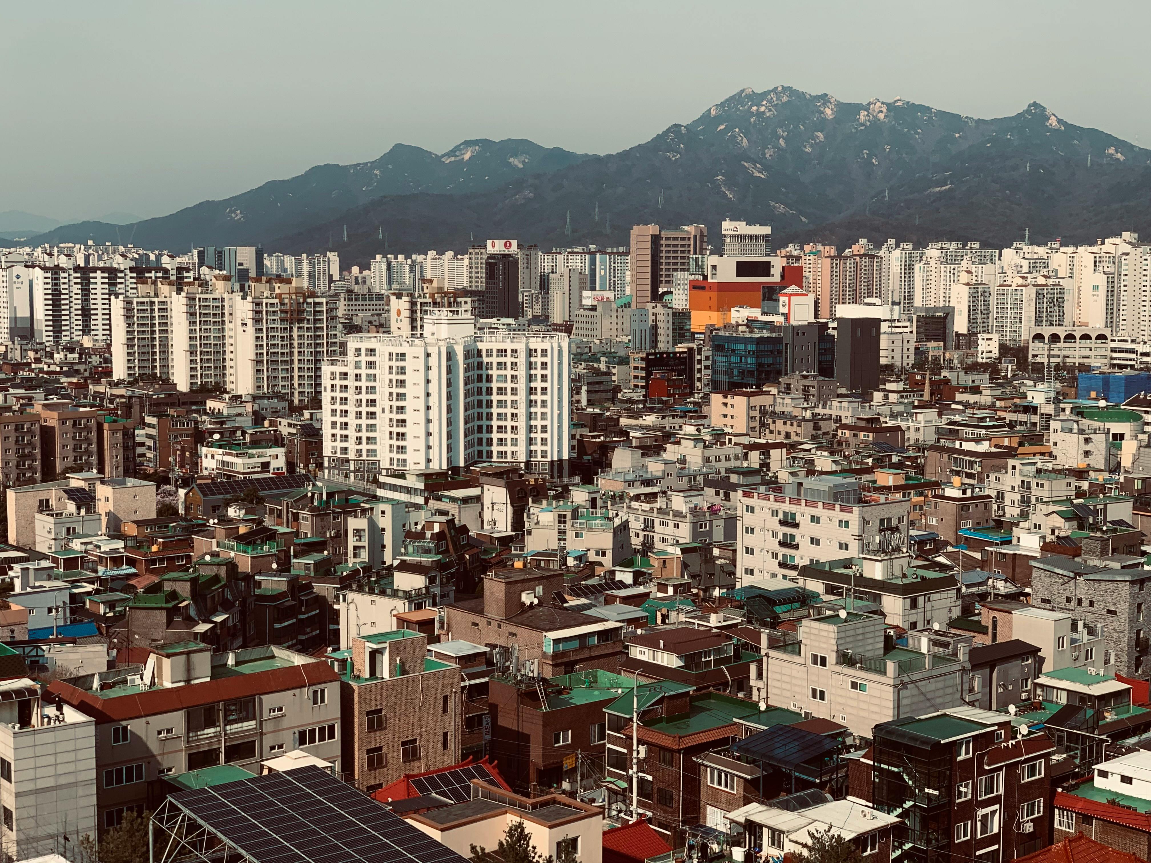 Aerial cityscape of Seoul with mountains, showcasing the urban density and architecture.