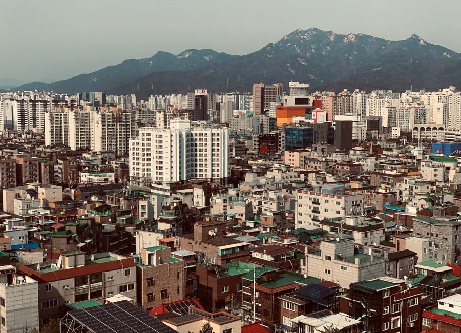 Aerial cityscape of Seoul with mountains, showcasing the urban density and architecture.
