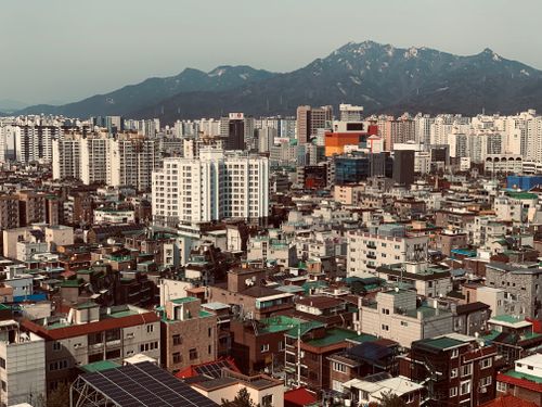 Free Aerial cityscape of Seoul with mountains, showcasing the urban density and architecture. Stock Photo