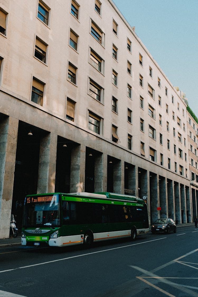 A Bus And Car On A Road Near The Building