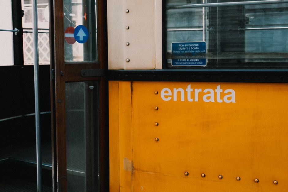 Detailed view of a yellow tram entrance with 'entrata' text and ticket warning sign.