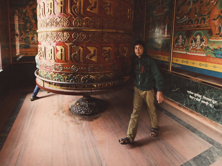 Teenager Near Ornamented Bell And Paintings In Temple