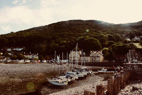 Boats on Dock Near Buildings and Green Mountain