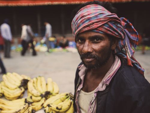 Free Portrait of a vendor selling bananas at an urban market, displaying cultural attire. Stock Photo