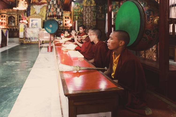 Tibetan Monks Sitting By Table Playing Instruments