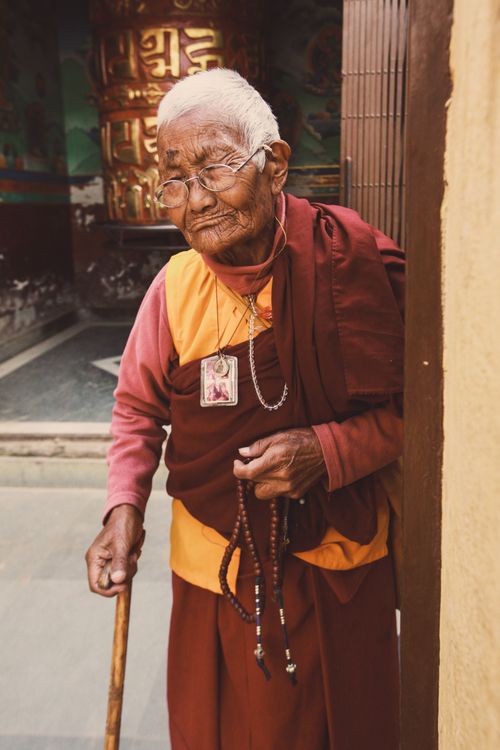 Free A senior adult monk holding prayer beads and walking stick, symbolizing spirituality and wisdom. Stock Photo