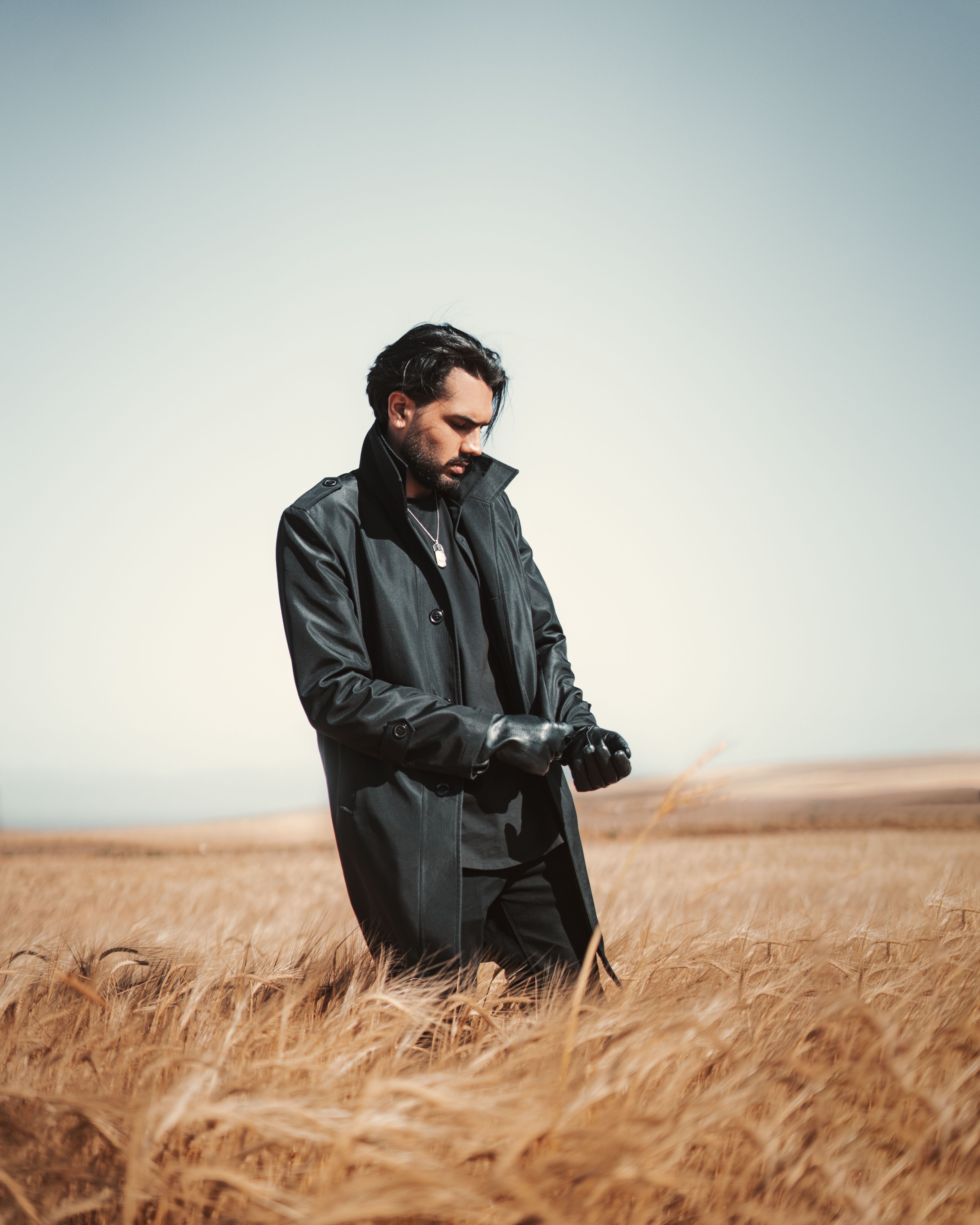 Man in dark coat standing in grass field countryside