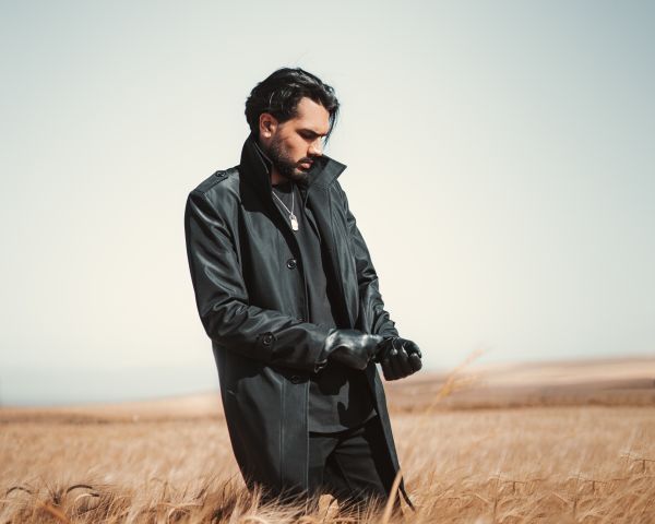 Man in dark coat standing in grass field countryside