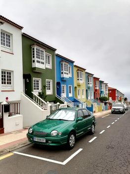 Vibrant row of colorful homes in Santa Cruz de Tenerife with parked cars in the foreground.