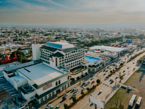 Drone shot capturing a vibrant cityscape with prominent hotel and busy highway. - Fotografer Sidoarjo