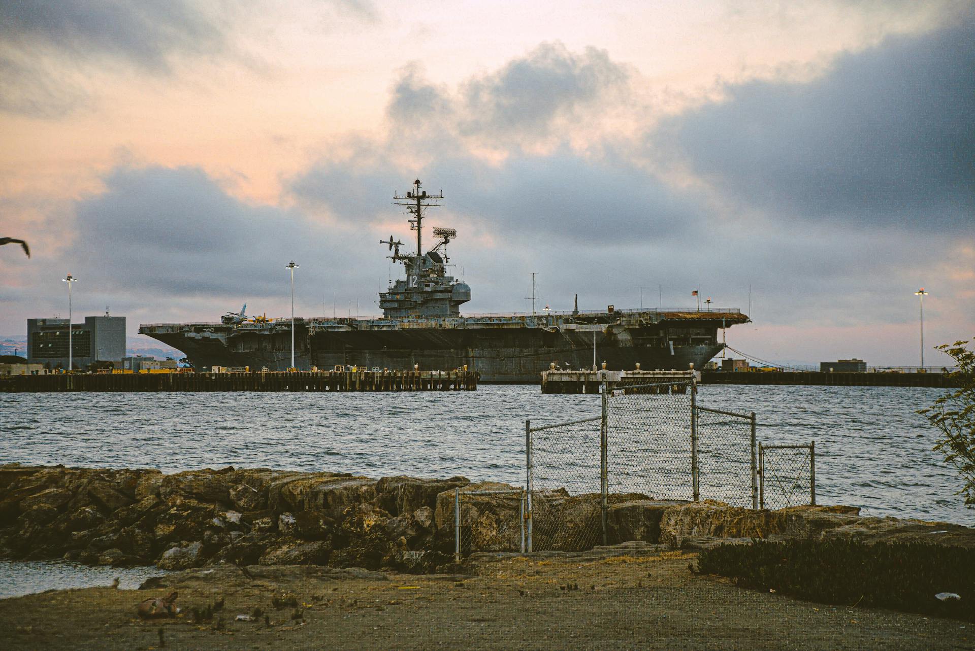A docked warship at the harbor during a dramatic twilight sky, showcasing maritime strength.