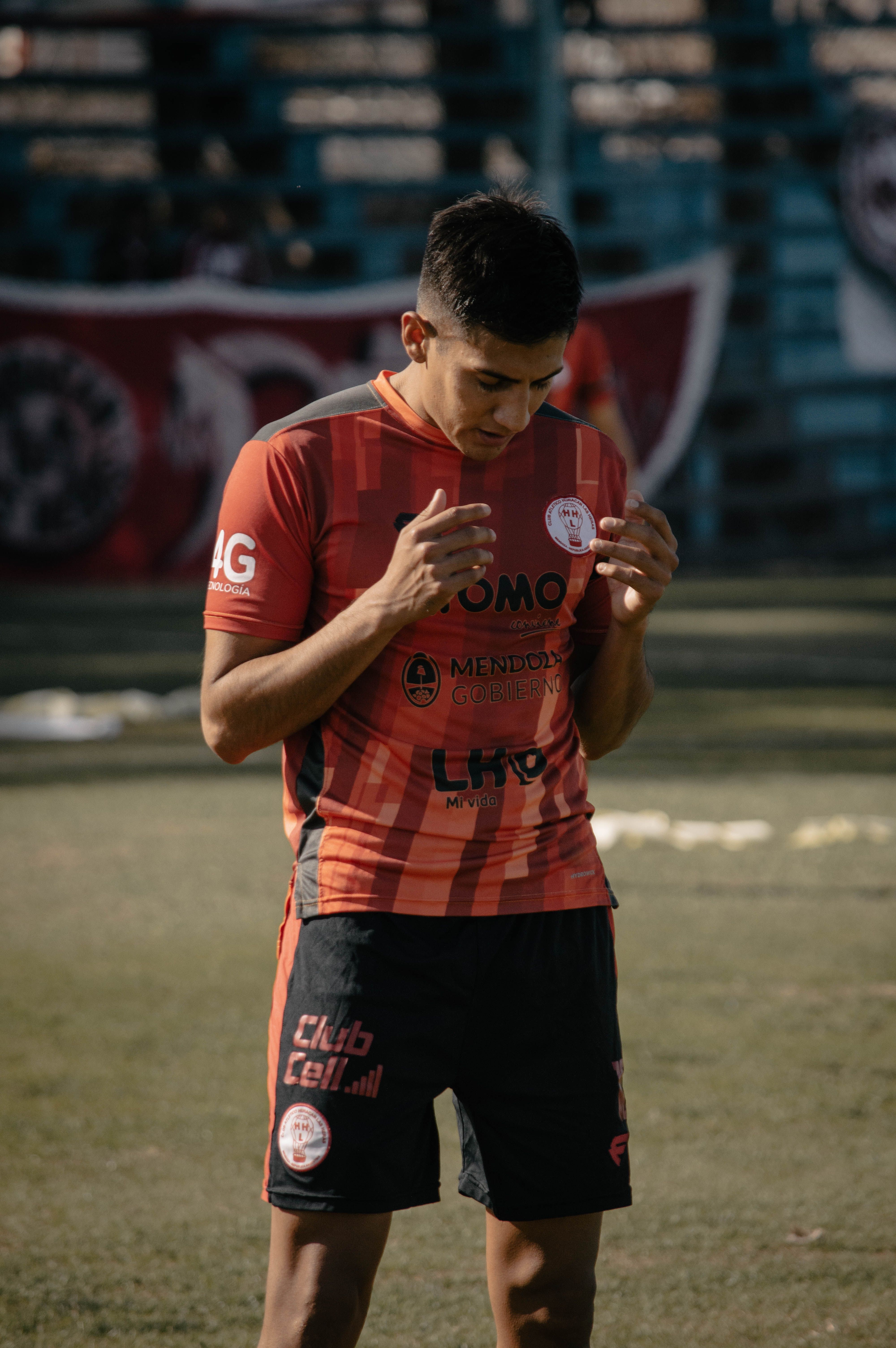 Young soccer player adjusting uniform on field in Mendoza, Argentina under daylight.