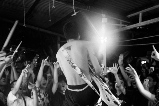 Black and white photo of a guitarist performing live at a crowded, energetic concert.