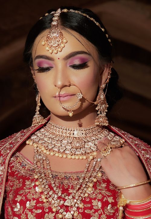 Free Portrait of a woman in traditional Indian bridal attire with intricate jewelry and makeup. Stock Photo