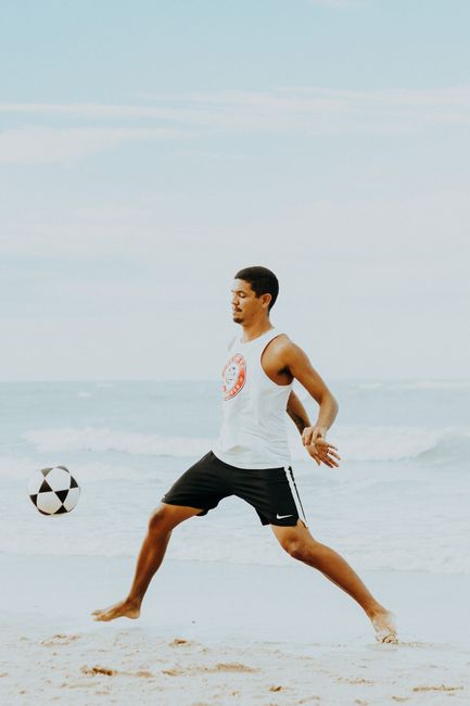 A young man plays soccer on the sandy beach of Canoa Quebrada, Brazil, enjoying a sunny day by the sea.
