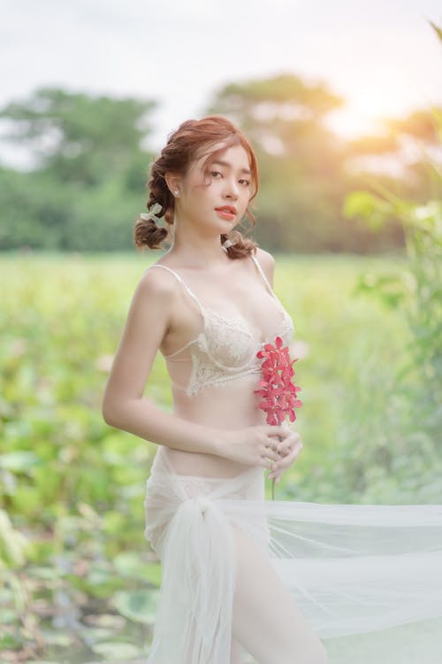 A Pretty Woman in White Brassiere Holding a Red Flower