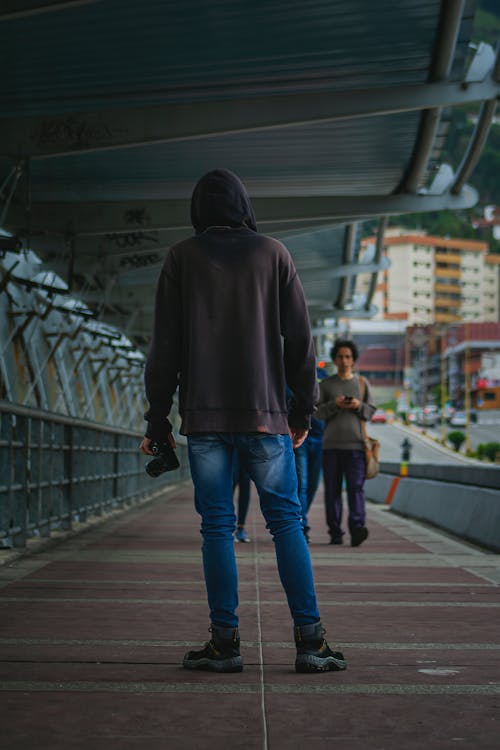 Foto profissional grátis de andando, câmera dslr, camisola com capuz