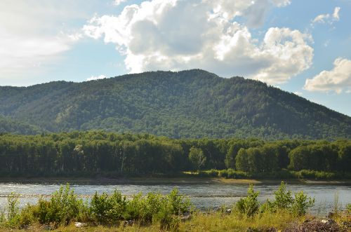 Free Peaceful mountain landscape with lush forest and serene lake under a bright sky. Stock Photo