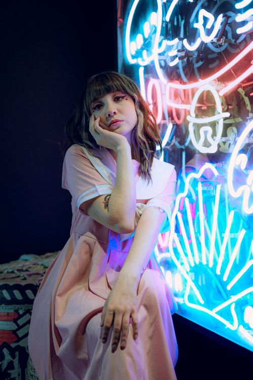 Free Young woman in pink dress posing against vibrant neon lights in Mexico City - moody and artistic urban scene. Stock Photo
