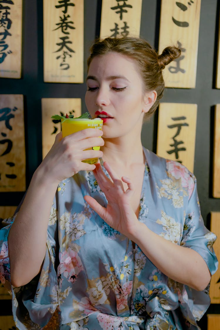 A Woman In A Floral Kimono Drinking A Cocktail