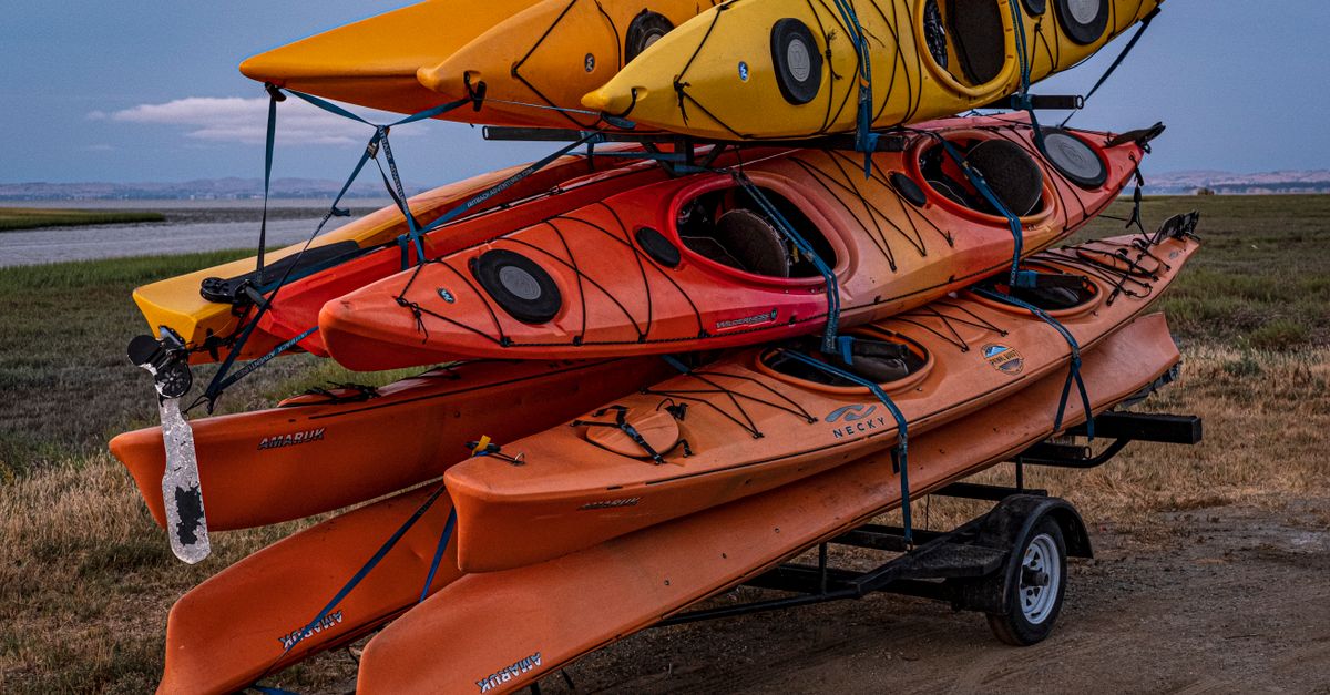 Colorful kayaks stacked on a trailer ready for adventure in a scenic outdoor setting.