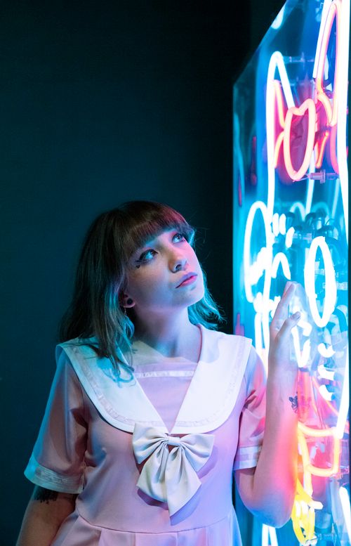 Free A woman in a pink dress looks thoughtfully at colorful neon lights, CDMX, Mexico. Stock Photo
