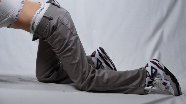 A Person Crawling While Wearing Gray Leather Pants 