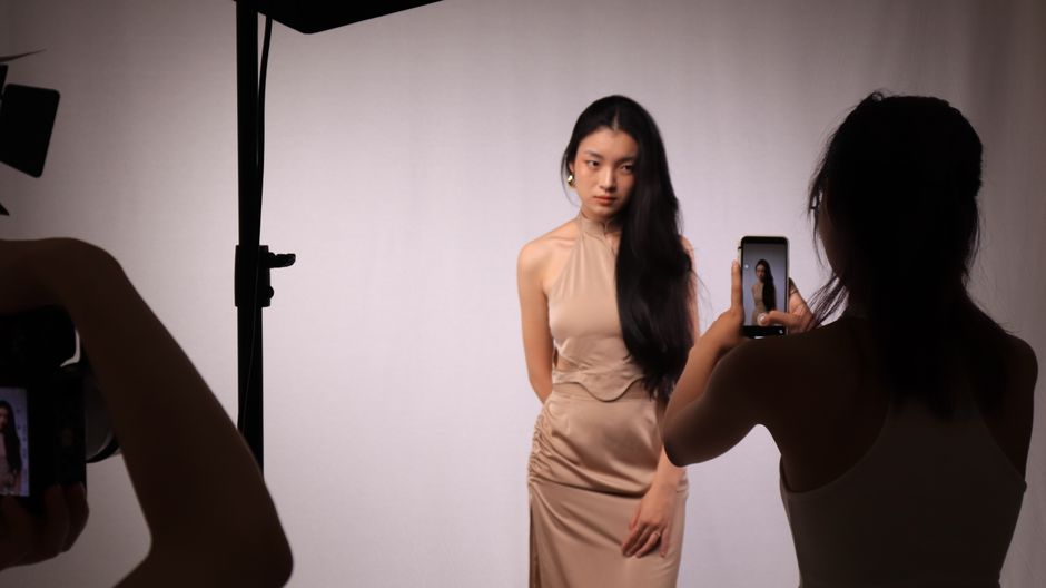 how to create a compelling professional portfolio - A professional studio photoshoot capturing a woman in a beige dress, using digital cameras and smartphones.