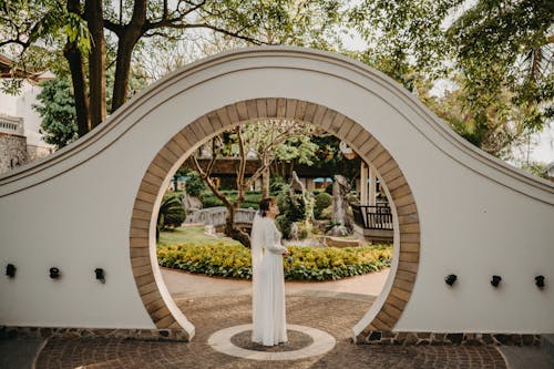 A Bride Wearing Beautiful Wedding Gown Standing on the Entrance while Posing at the Camera